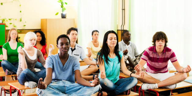 Group of teenagers sitting on the desk in lotus position.